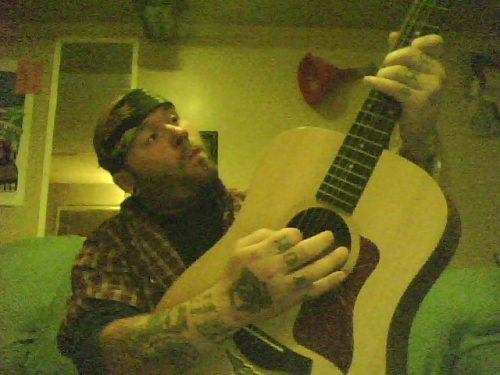 Wes Kime of Brothers KIME playing guitar with a bandana on, mid-session, reflecting the band’s gritty, DIY recording approach.