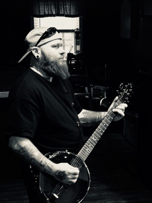Wes Kime holding a banjo during a Brothers KIME session, highlighting the band’s blend of folk, rock, and experimental sounds.